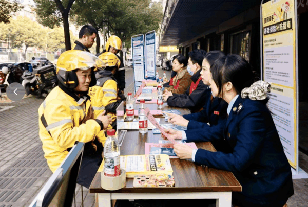 2025年12月10日，湖南湘潭，骑手向当地有关部门工作人员咨询社保补贴相关事宜。张杰　摄