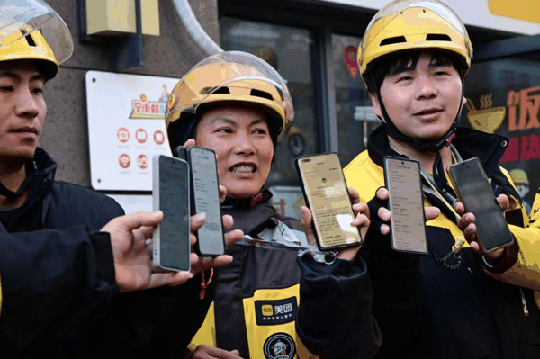 2025年12月10日，江苏南京，骑手们展示收到社保补贴的手机页面信息。李硕　摄