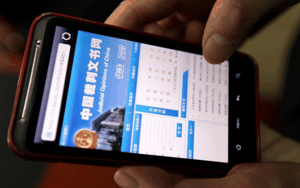▲一名市民在手机上浏览“中国裁判文书网”。图/IC photo