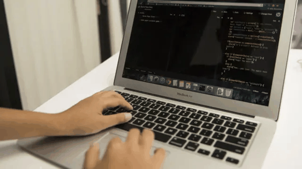 一位用家双手在一台灰色 MacBook Air 上输入编程