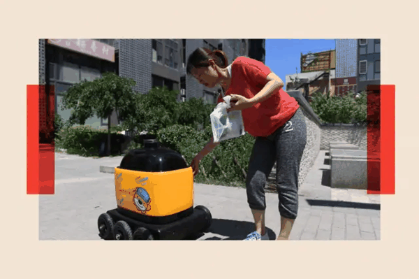 一名女子在住宅小区取走由臻机器人（Zhen Robotics）的配送机器人送来的杂货。