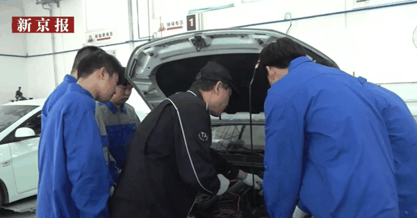 在北京市商业学校魏工养车实训区,学生们在企业教师的指导下学习汽修知识。直播截图