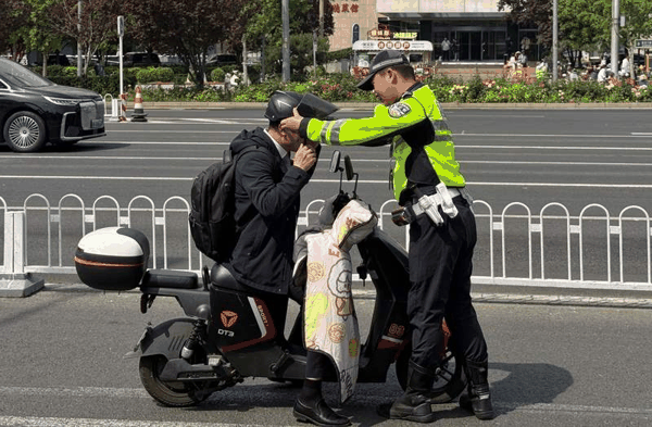 执勤交警现场指引一位市民按照规范戴好头盔，不能只携带而不佩戴。新京报记者 王贵彬 摄