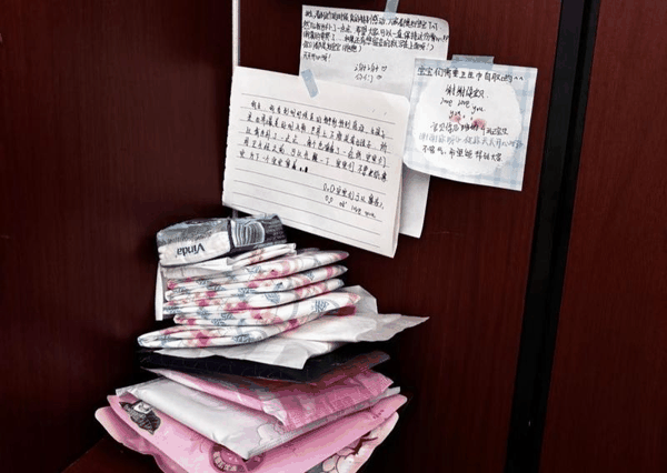 ▲学校初中部女厕所隔间角落里摆放着多款卫生巾，还有同学们留下的暖心便签。图/现代快报