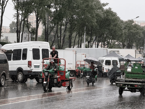 新发地市场商户雨中运送蔬菜。受访者供图