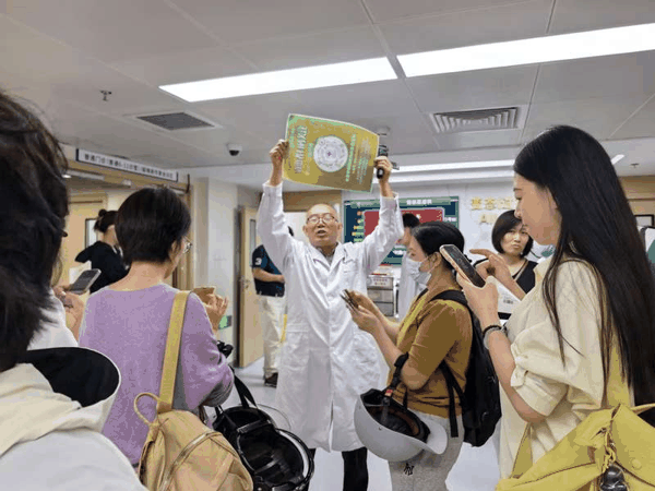一位医务人员举着一张二维码打印纸，邀请患者扫码关注科室在某社交平台的视频号。新京报记者 戴轩 摄