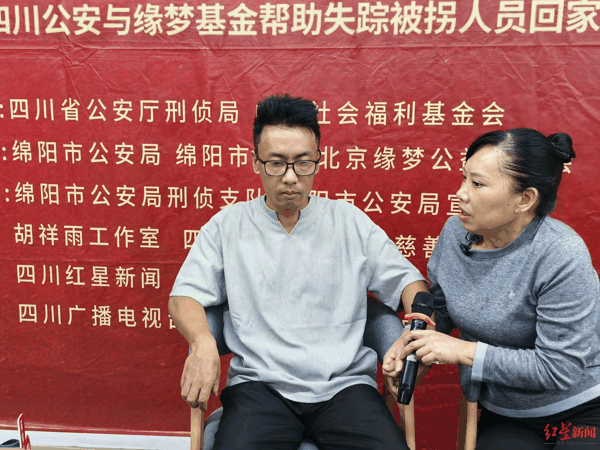 ▲认亲团圆现场，刘华清紧紧拉着儿子的手