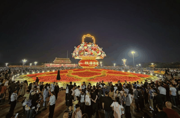 夜晚亮灯的“祝福祖国”大花篮吸引游客拍照。新京报记者 薛珺 摄