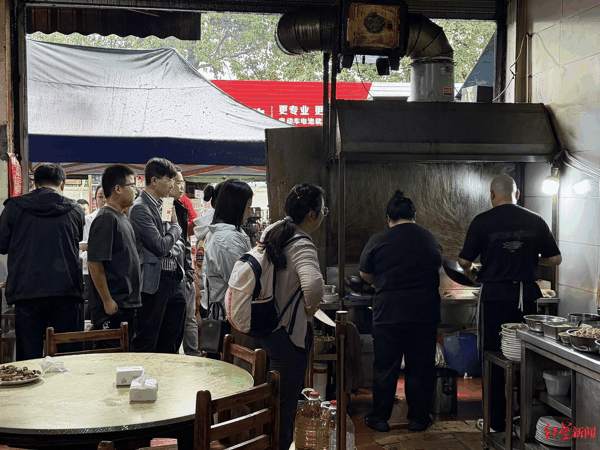 ▲餐馆炒菜现场围满等候的食客