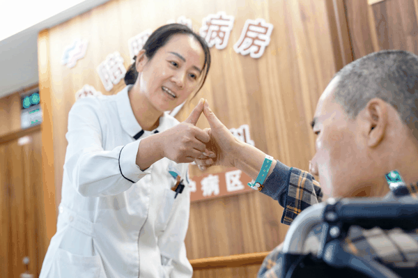 浙江省湖州市安吉县中医院老年医学科的病区内，医护人员指导老年患者开展康复训练，暖意融融。图片来源：视觉中国